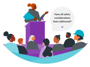 A diverse group listens intently as a speaker at a podium addresses safety considerations, with a dialogue bubble emphasizing the question.