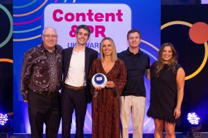 Constructionline Marketing team and the Marketing Pod team stand together on the stage celebrating an award at the Content & PR UK Awards event
