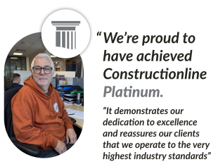 Dave Primmett sits at a desk surrounded by paperwork, expressing pride in achieving Constructionline Platinum status.