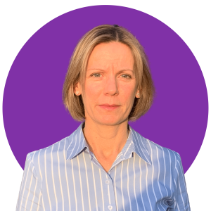 Sam Downie wears a blue and white striped shirt, standing in front of a vibrant purple circular backdrop.
