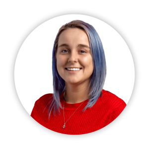 Person with shoulder-length light purple hair wearing a red ribbed sweater and a silver pendant necklace, shown on a white circular background.